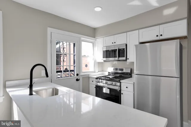 a kitchen with stainless steel appliances a refrigerator sink and white cabinets