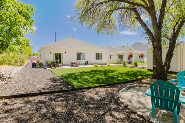 287 East 1000 North Logan, UT 84321 - Photo 39 of 41 Expansive backyard featuring a large artificial turf lawn, a gravel pathway, a concrete patio, and a mature shade tree