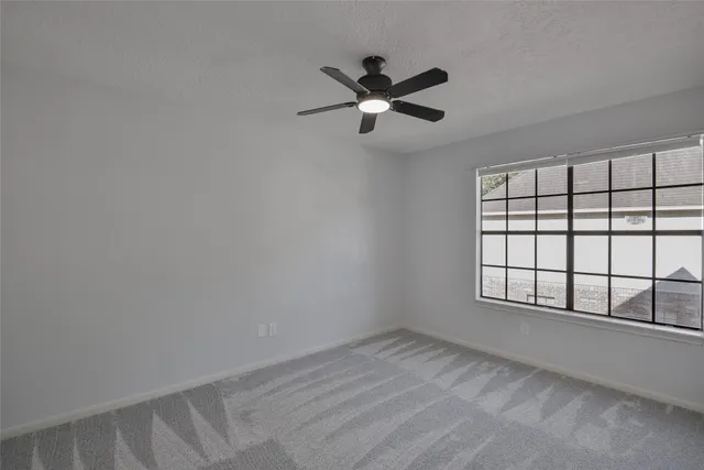 an empty room with windows and fan