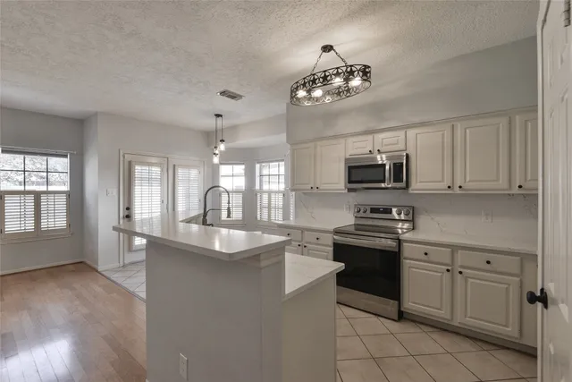 a kitchen with stainless steel appliances granite countertop a sink dishwasher stove top oven and cabinets with wooden floor