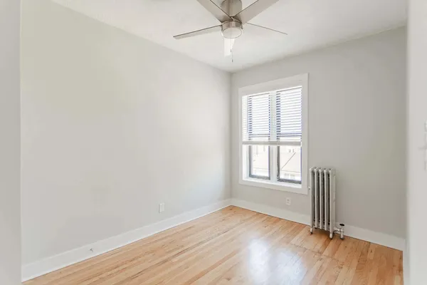 an empty room with wooden floor chandelier fan and windows