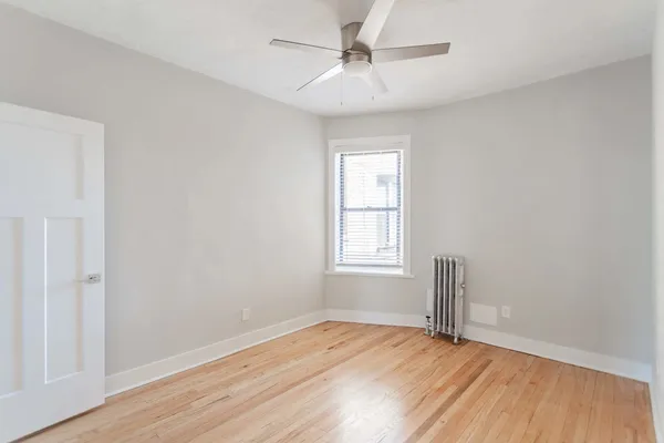 an empty room with wooden floor fan and windows