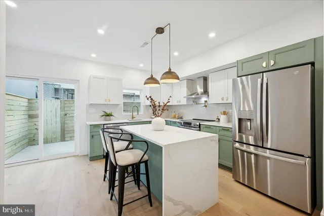 a kitchen with stainless steel appliances a refrigerator a stove a sink a dining table and chairs