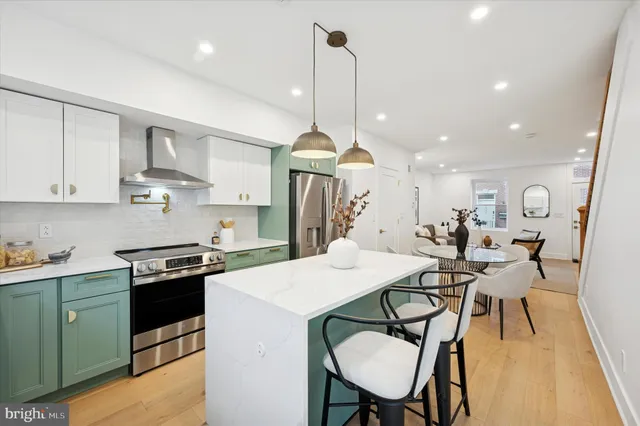 a kitchen with stainless steel appliances kitchen island granite countertop a stove a sink a dining table and chairs with wooden floor