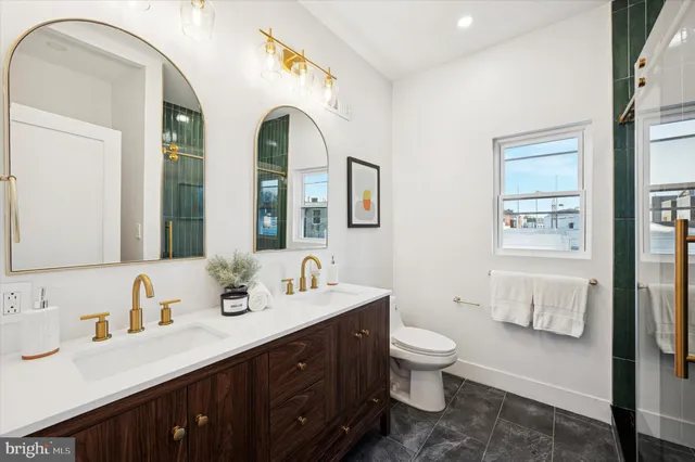 a spacious bathroom with a double vanity sink a mirror and a toilet