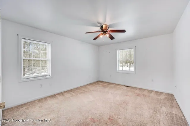 a view of a big room with windows and chandelier fan