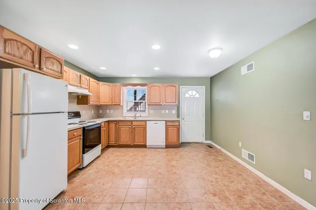 a kitchen with stainless steel appliances granite countertop a refrigerator and a stove top oven