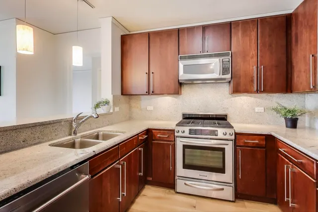 a kitchen with granite countertop wood cabinets stainless steel appliances and a sink