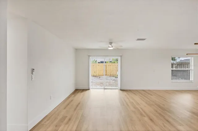 a view of an empty room with wooden floor and a window