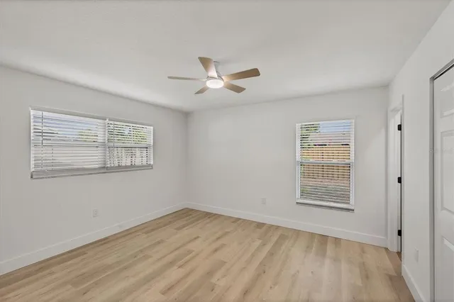 a view of an empty room with a window and wooden floor