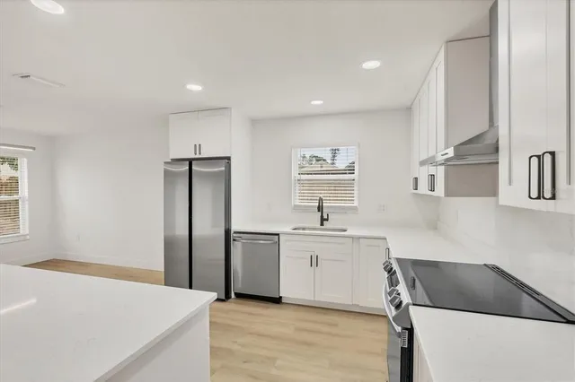 a kitchen with a sink a stove a refrigerator and white cabinets