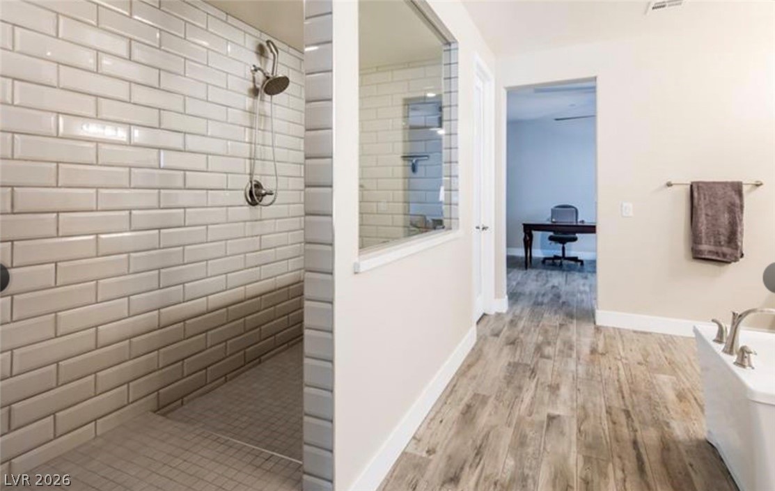 4631 Amazing View Street Las Vegas, NV 89129 - Photo 16 of 33 A well-appointed bathroom features subway tile shower and durable plank flooring leading to an adjoining room.