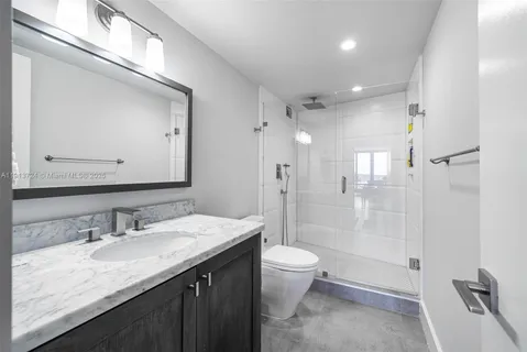 a bathroom with a granite countertop sink a toilet a mirror and shower
