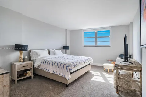 a bedroom with a bed and a flat tv screen on the dresser