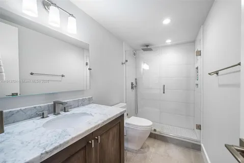 a bathroom with a granite countertop sink a toilet and shower