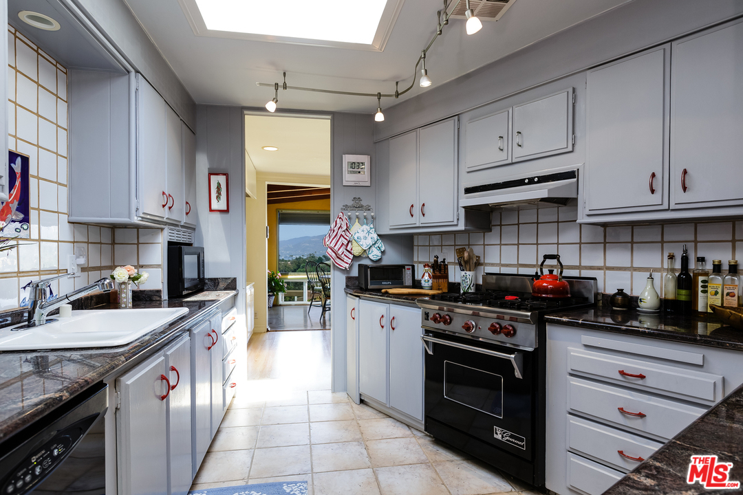 29500 Heathercliff Road, Unit 202 Malibu, CA 90265 - Photo 14 of 30 a kitchen with stainless steel appliances granite countertop a sink a stove and cabinets