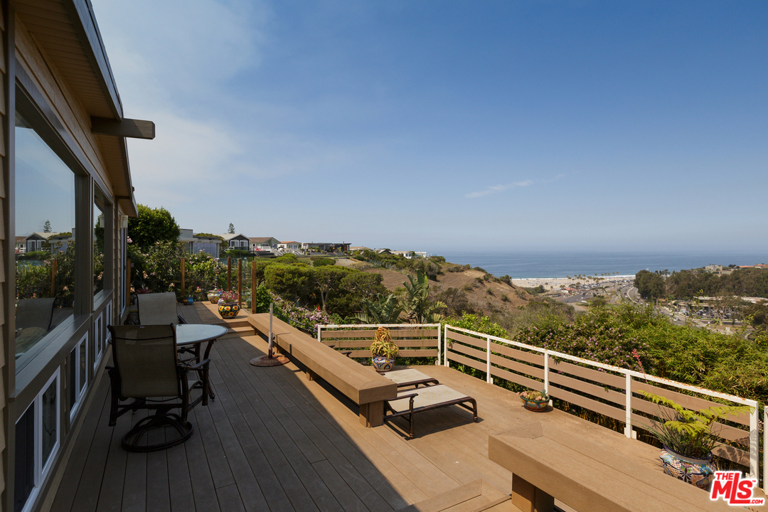 29500 Heathercliff Road, Unit 202 Malibu, CA 90265 - Photo 3 of 30 a view of a balcony with chairs and wooden floor