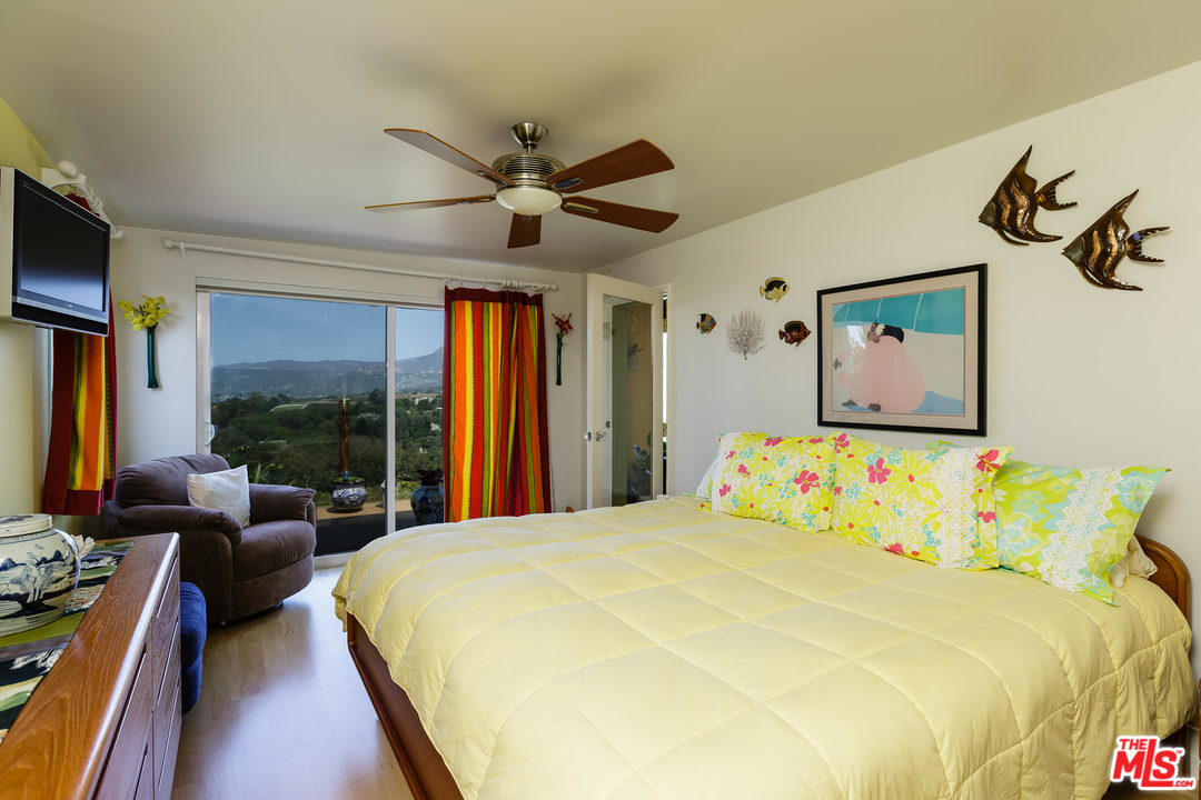 29500 Heathercliff Road, Unit 202 Malibu, CA 90265 - Photo 23 of 30 a bedroom with a large bed and a flat tv screen