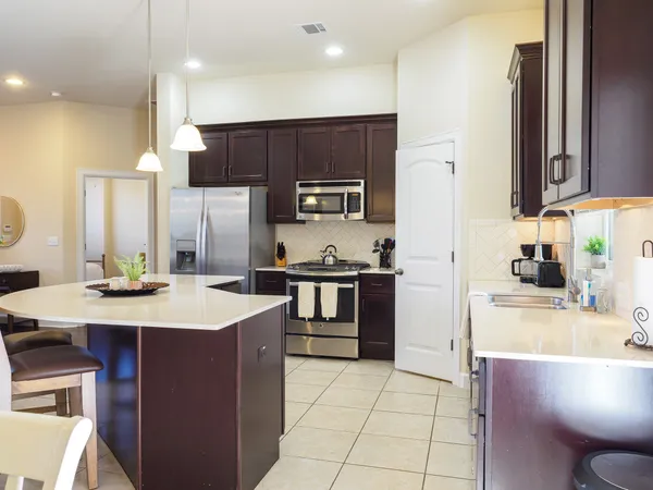 a kitchen with stainless steel appliances kitchen island granite countertop a table chairs microwave and sink