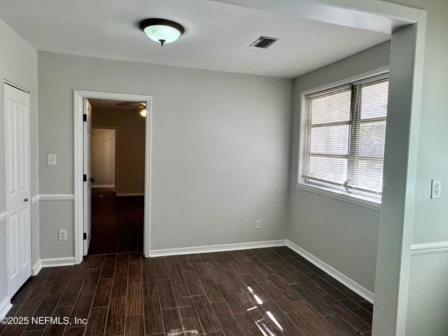a view of empty room with wooden floor and fan