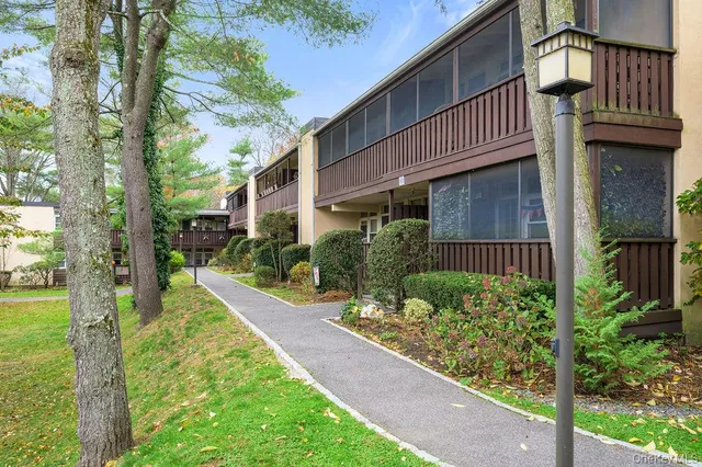 a view of a house with a small yard plants and large tree