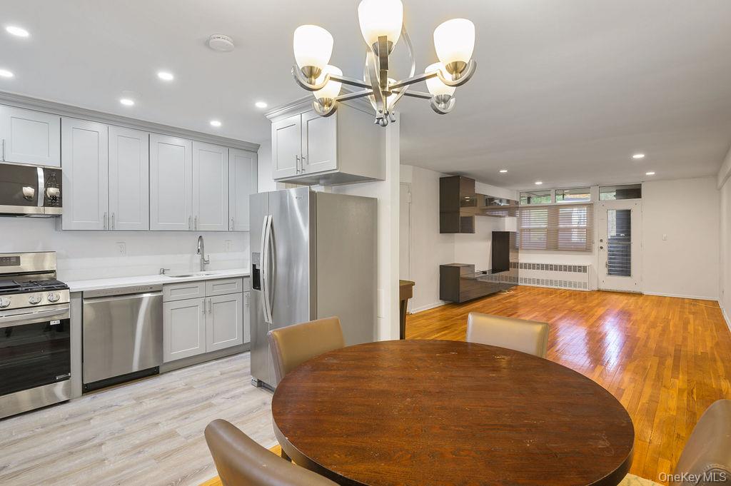 103 Wiltshire Road, Unit D6 Scarsdale, NY 10583 - Photo 6 of 20 a large kitchen with stainless steel appliances kitchen island granite countertop a stove a refrigerator a oven a dining table and chairs with wooden floors