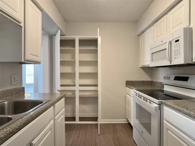 a kitchen with granite countertop a sink dishwasher stove and cabinets