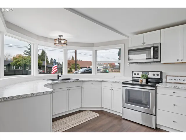 a kitchen with stainless steel appliances granite countertop a sink a stove and cabinets