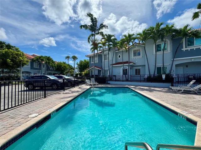 a view of a house with swimming pool lawn chairs and a yard
