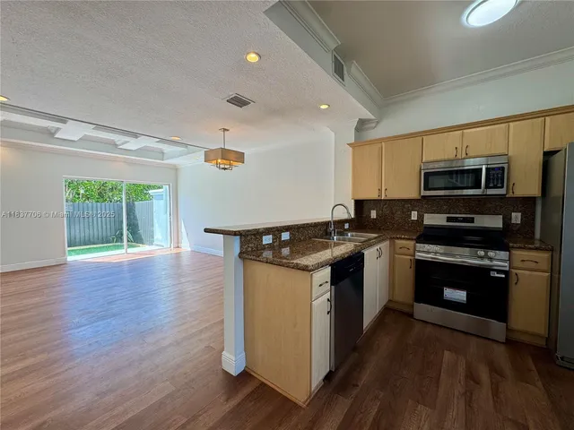 a kitchen with granite countertop a refrigerator stove and sink