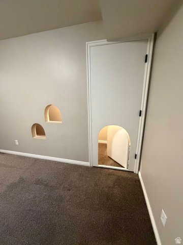 1563 South 600 East Springville, UT 84663 - Photo 24 of 30 Neutral wall paint, two arched wall niches with interior lighting, a full-height interior door, an arched opening within the door, and dark carpet flooring