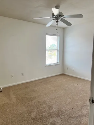 an empty room with a chandelier fan and windows