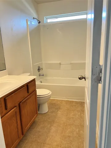 a bathroom with a granite countertop bathtub shower sink vanity and toilet