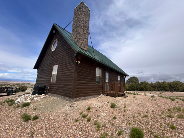 19075 West Honesty Cove Duchesne, UT 84021 - Photo 34 of 44 Log cabin exterior with a green metal roof and a prominent stone chimney