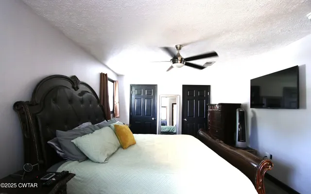 a bedroom with a large bed and a flat tv screen on a dresser