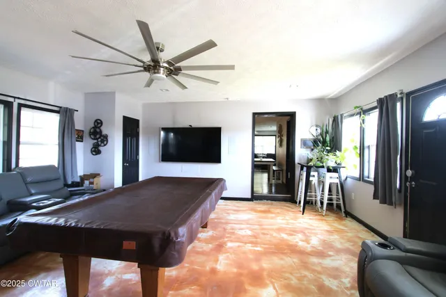 a living room with furniture a flat screen tv and a refrigerator