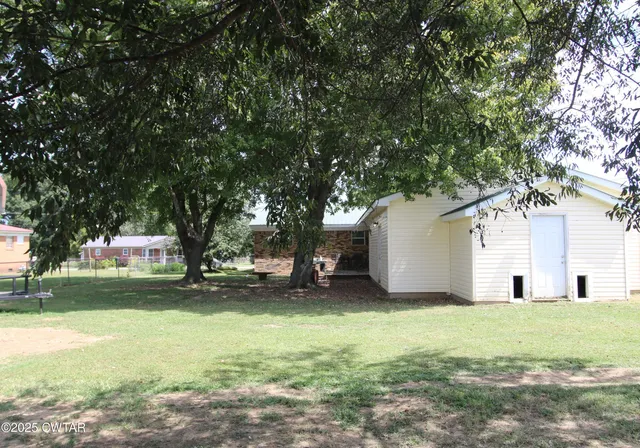 a view of a house with a yard and large trees