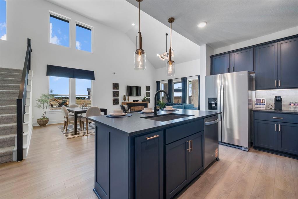 9301 Shadow Trail Little Elm, TX 75068 - Photo 2 of 10 a kitchen with stainless steel appliances granite countertop a refrigerator a sink dishwasher a stove and a dining table with wooden floor