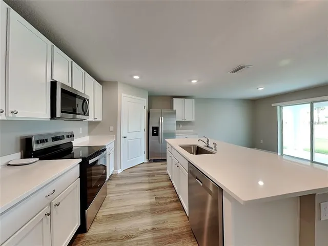 a kitchen with a sink a counter top space stainless steel appliances and cabinets
