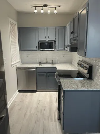 a kitchen with stainless steel appliances granite countertop a sink a stove a refrigerator and cabinets