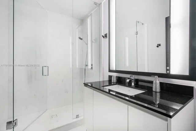 a bathroom with a granite countertop sink a mirror and a shower