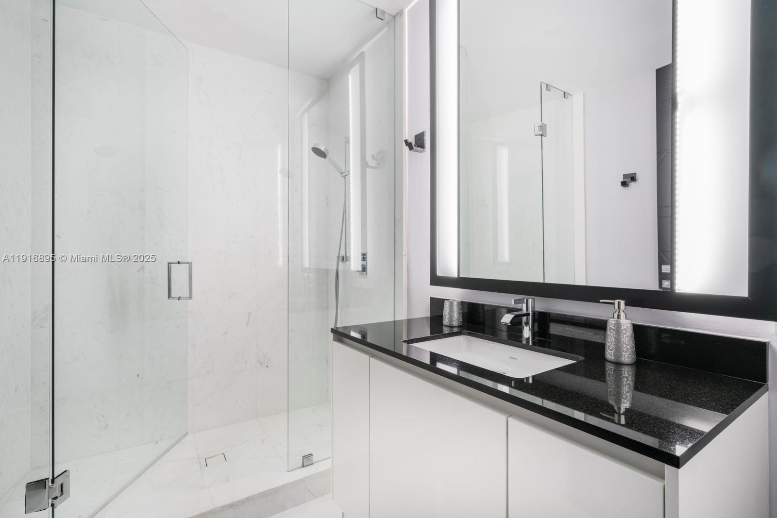 18555 Collins Avenue, Unit 3505 Sunny Isles Beach, FL 33160 - Photo 10 of 52 a bathroom with a granite countertop sink a mirror and a shower