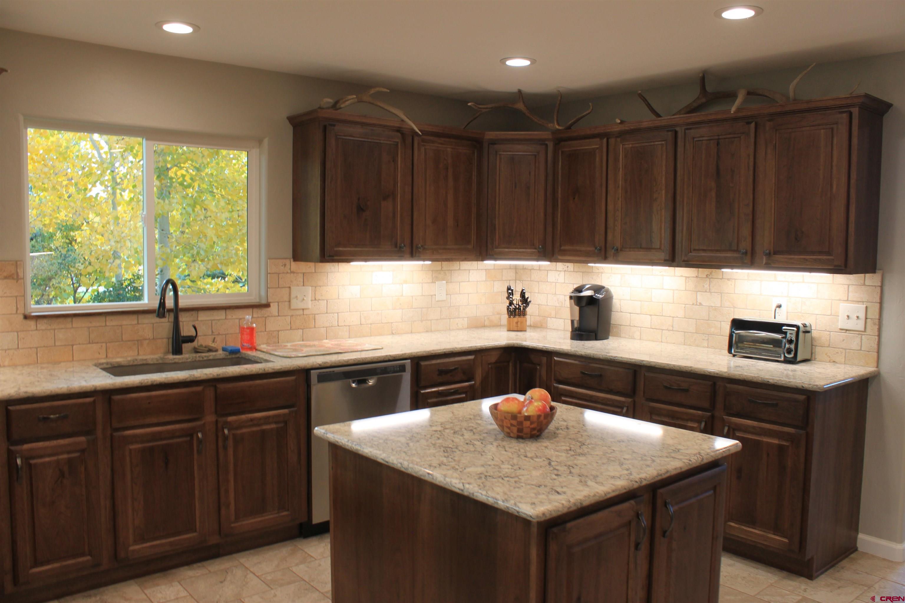 20976 6840th Road Montrose, CO 81403 - Photo 4 of 33 a kitchen with a sink a stove a kitchen island a stove and a window