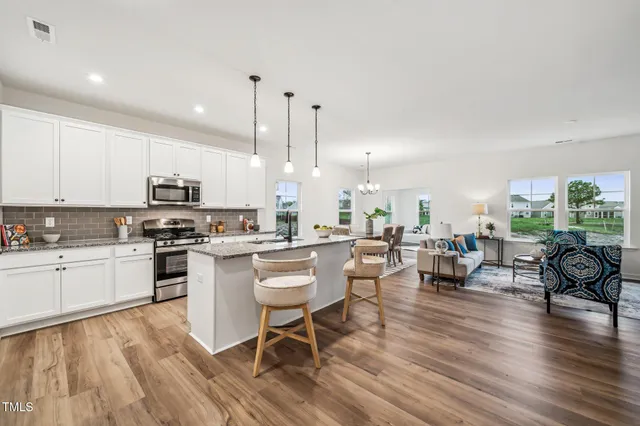 a large white kitchen with granite countertop lots of counter top space and stainless steel appliances