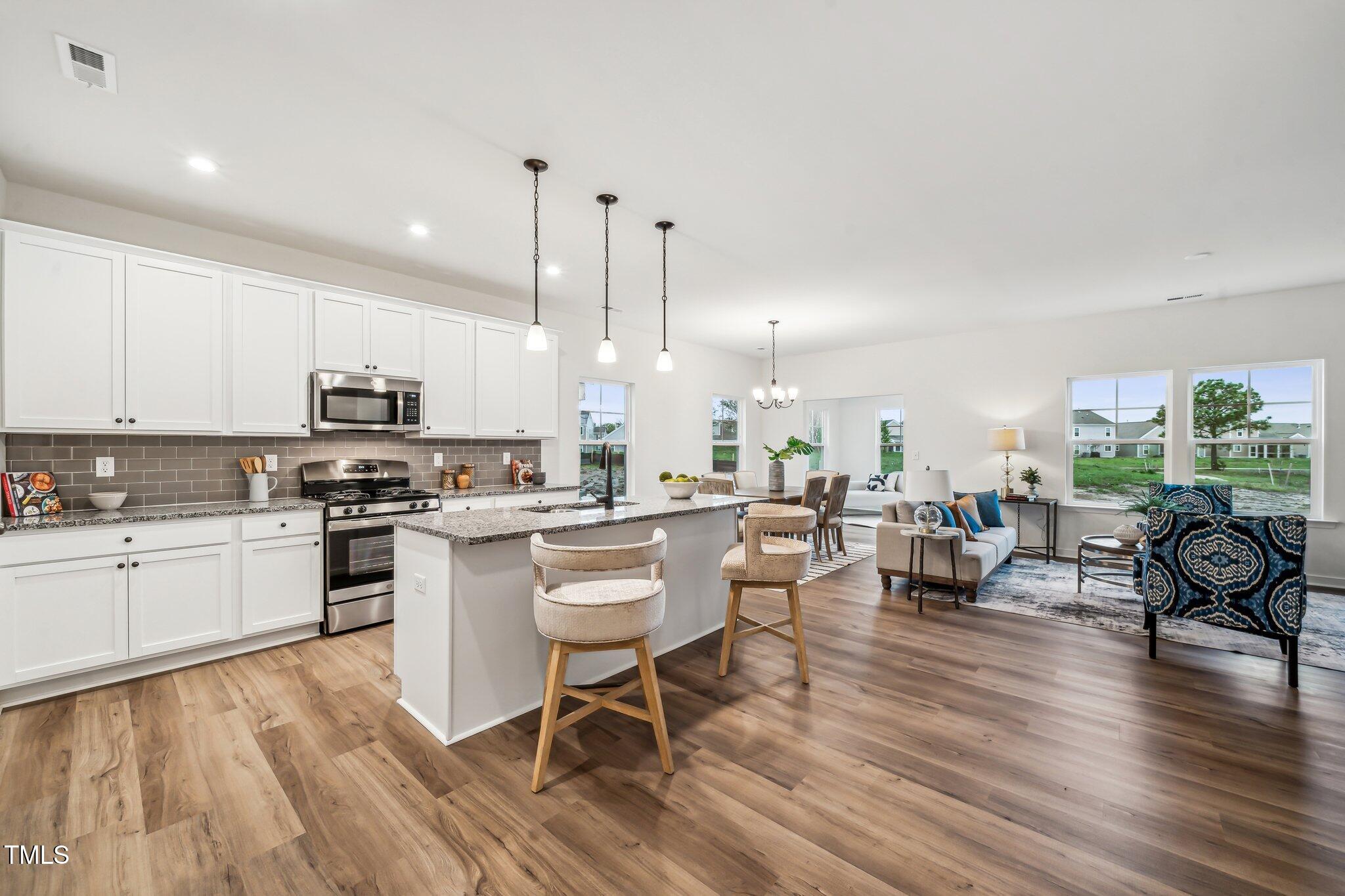 a large white kitchen with granite countertop lots of counter top space and stainless steel appliances
