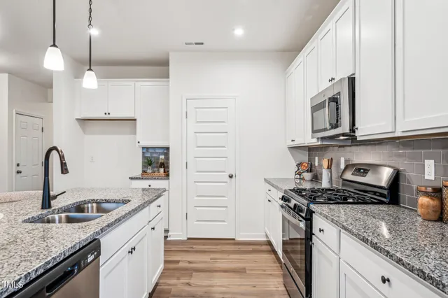 a kitchen with stainless steel appliances granite countertop a sink stove and cabinets