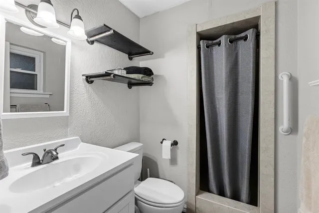 a bathroom with a sink a toilet a mirror and shower