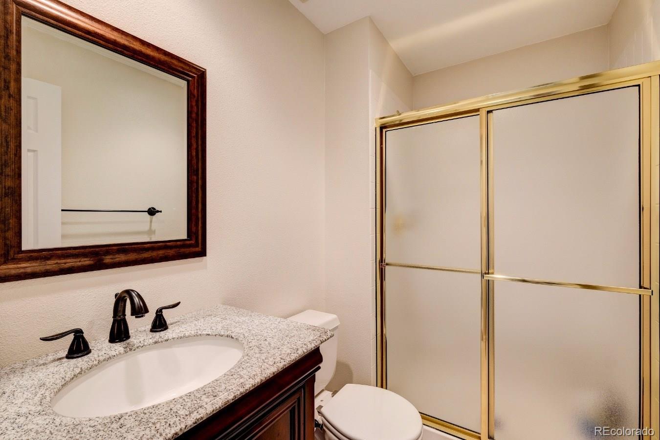 8927 Mountain Laurel Way Highlands Ranch, CO 80126 - Photo 16 of 35 a bathroom with a granite countertop sink mirror vanity and toilet