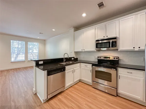 a kitchen with granite countertop a stove a sink and a microwave
