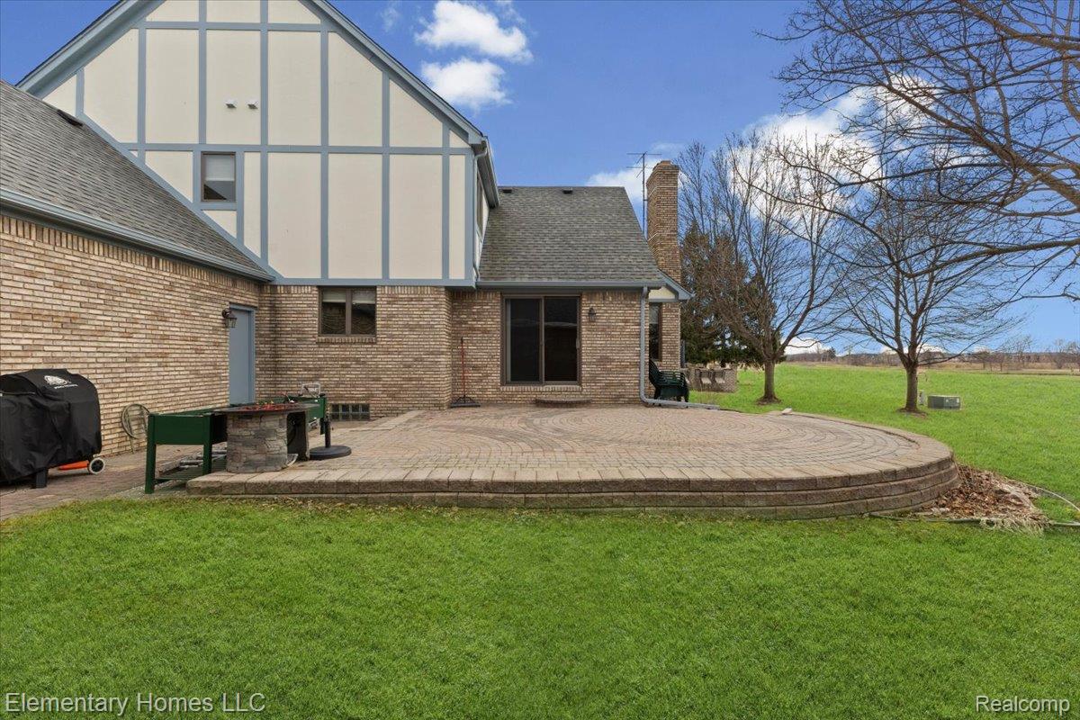 51637 Baker Road New Baltimore, MI 48047 - Photo 6 of 47 Rear view of house with a yard, brick siding, a chimney, roof with shingles, and a patio area